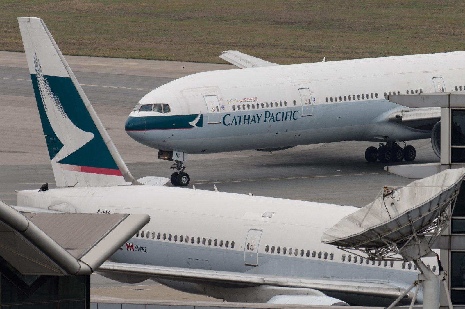 A Cathay Pacific Boeing 777 passenger aircraft (top) taxis past a stationary plane on the tarmac at the international airport in Hong Kong, China, March 15, 2017. (AFP File Photo)