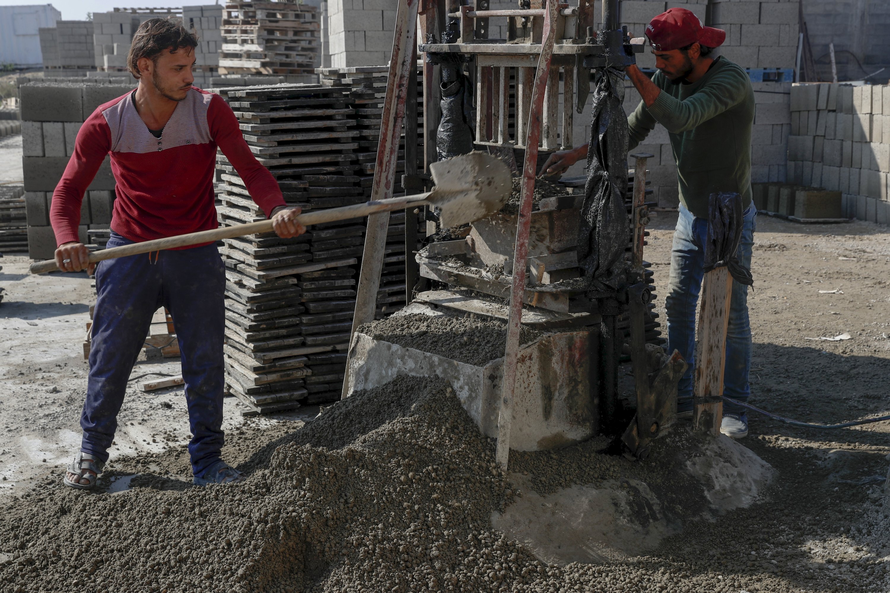 Palestinian workers make concrete bricks from recycled rubble of  buildings to be used in reconstruction of buildings that were damaged by Israeli airstrikes during Israel's war with Gaza's Hamas rulers last May, at a brick factory east of Gaza City, Jan. 6, 2022. (AP Photo)