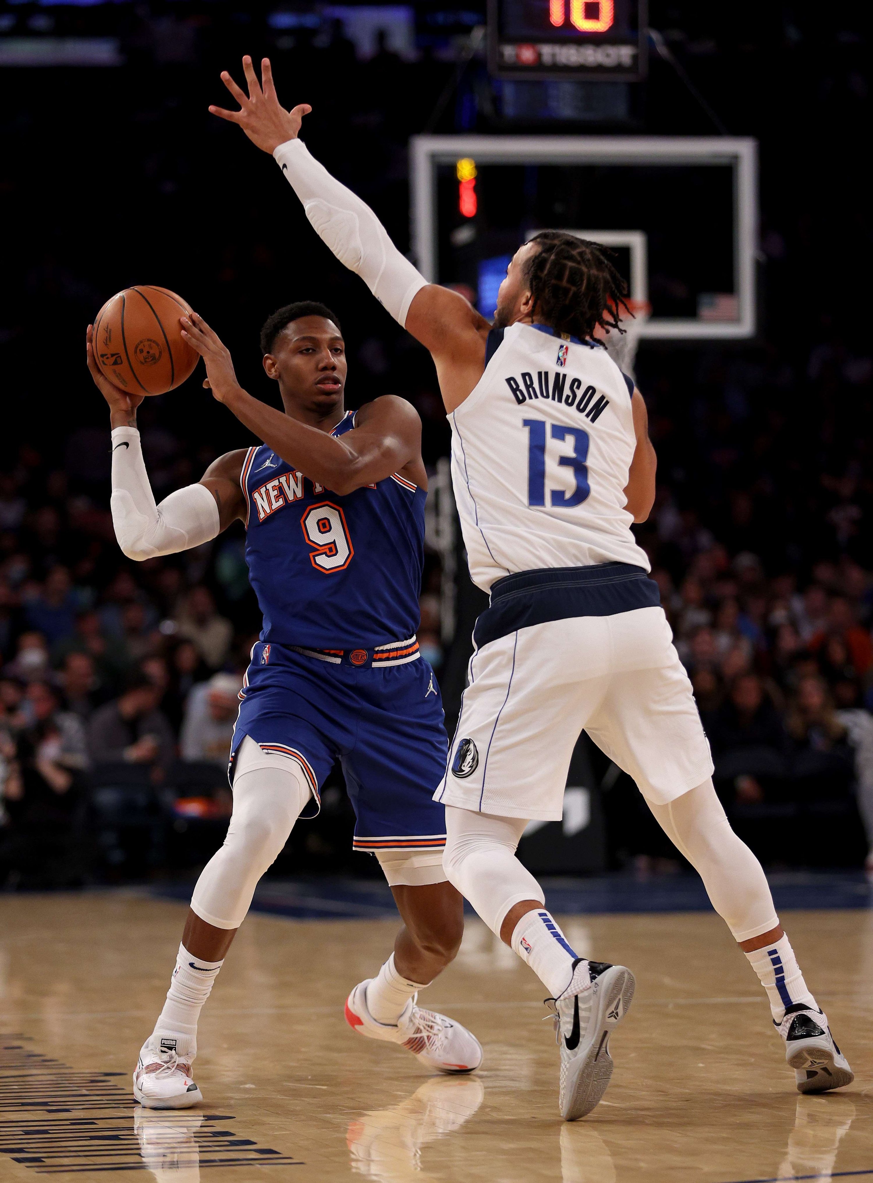 RJ Barrett dari New York Knicks (kiri) mencoba mengoper saat Jalen Brunson dari Dallas Mavericks bertahan dalam pertandingan NBA di New York City, AS, 12 Januari 2022. (AFP Photo)