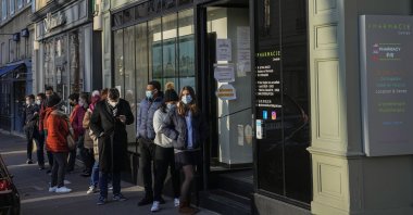 People wearing face masks to protect against COVID-19 lining up for vaccines and COVID-19 tests at a pharmacy in Versailles, west of Paris, Jan. 11, 2022. (AP Photo)