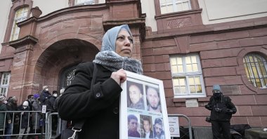 Yasmen Almashan holds pictures of her five brothers who died in Syria before the verdict was announced in front of the court in Koblenz, Germany, Jan. 13, 2022. (AP Photo)