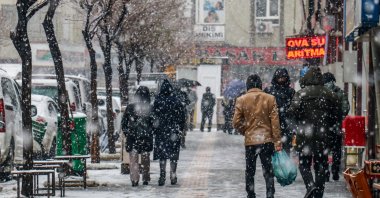 People walk on the street amid snowfall, in Van, eastern Turkey, Jan. 13, 2022. (AA PHOTO) 