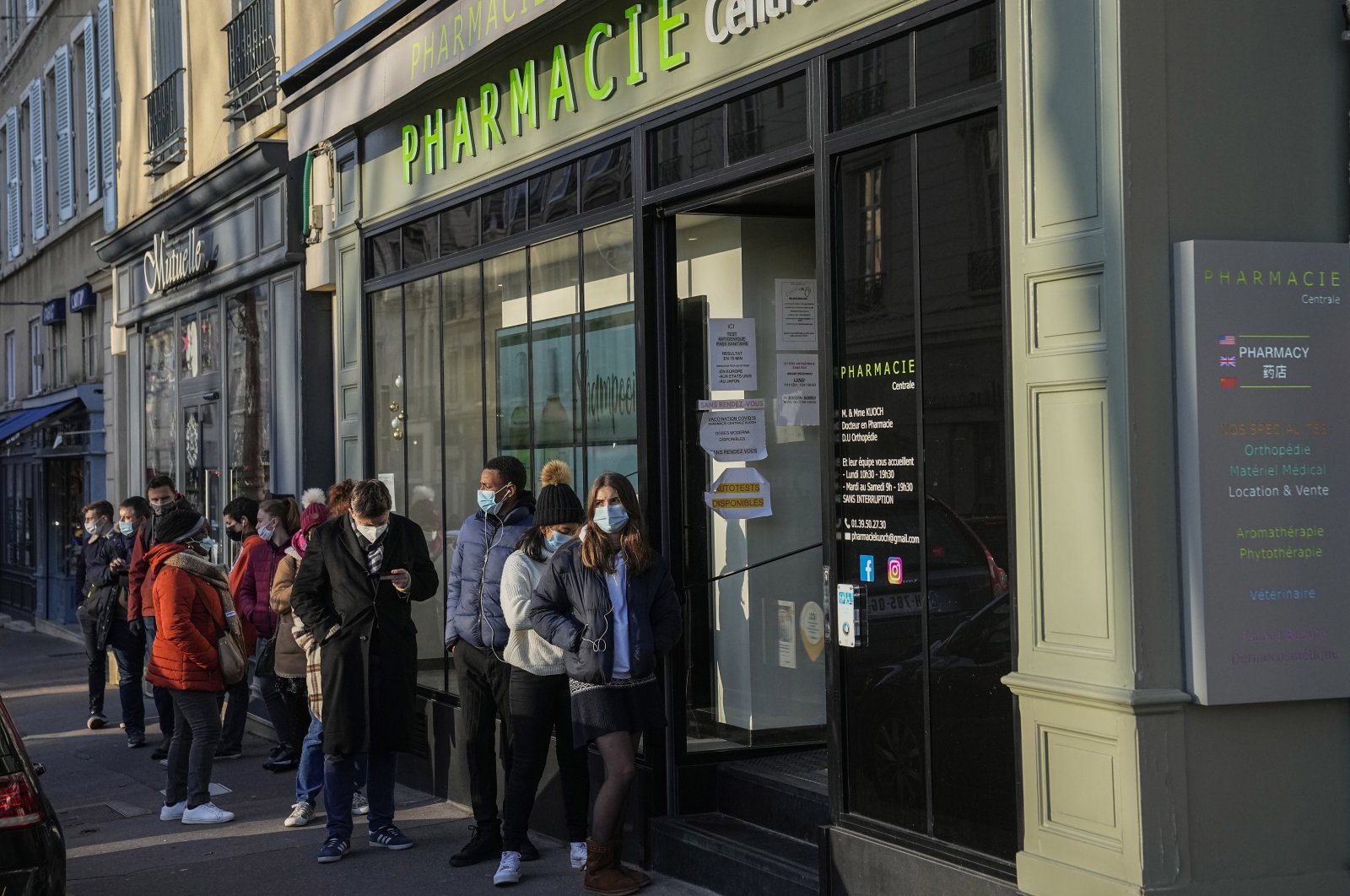 People wearing face masks to protect against COVID-19 lining up for vaccines and COVID-19 tests at a pharmacy in Versailles, west of Paris, Jan. 11, 2022. (AP Photo)