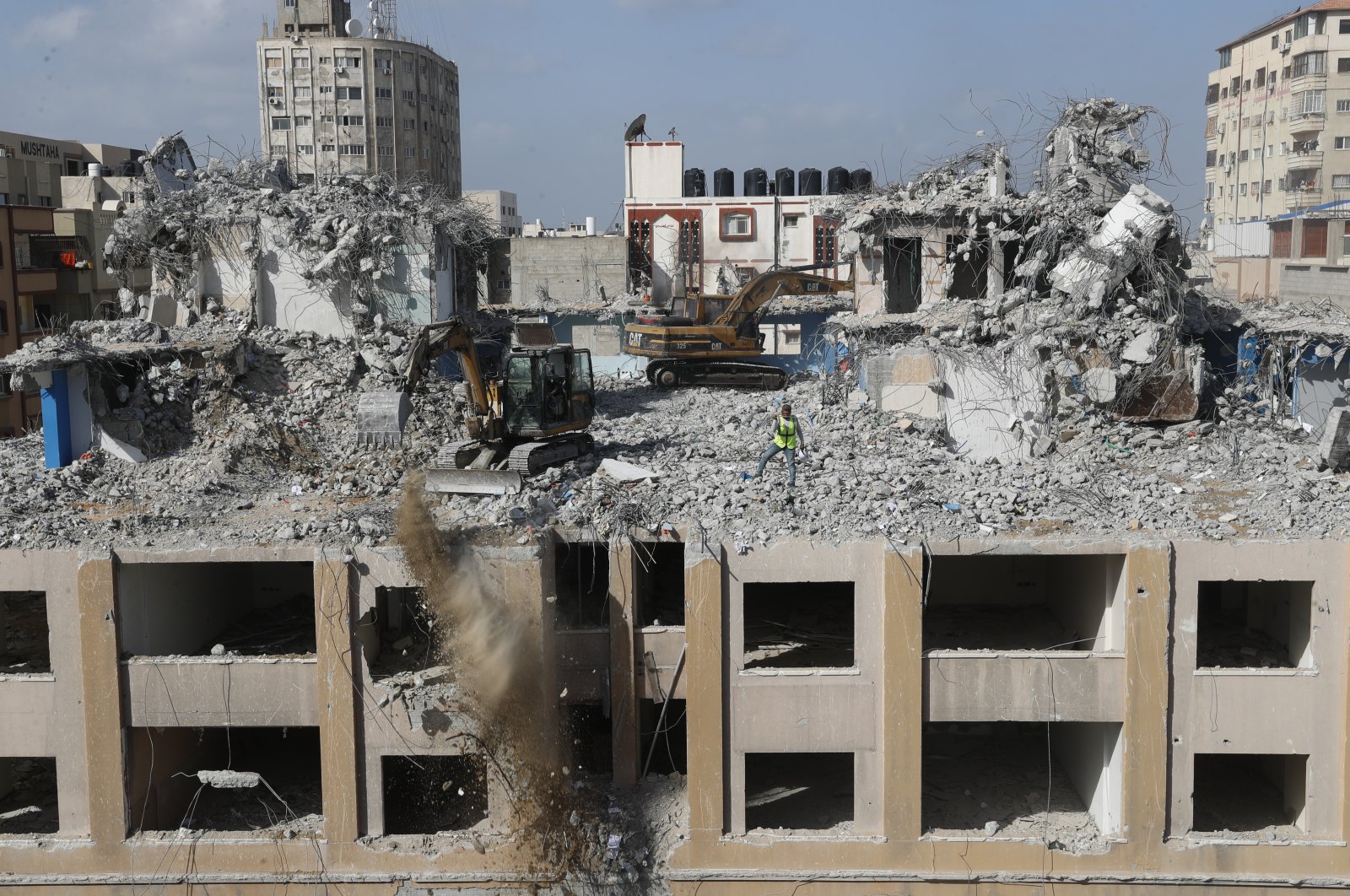 Palestinian workers use backhoes to break and remove parts of the al-Jawhara building, which was damaged by Israeli airstrikes during Israel&#039;s war with Gaza&#039;s Hamas rulers last May, in the central al-Rimal neighborhood of Gaza City, Palestine, Dec. 23, 2021. (AP Photo)