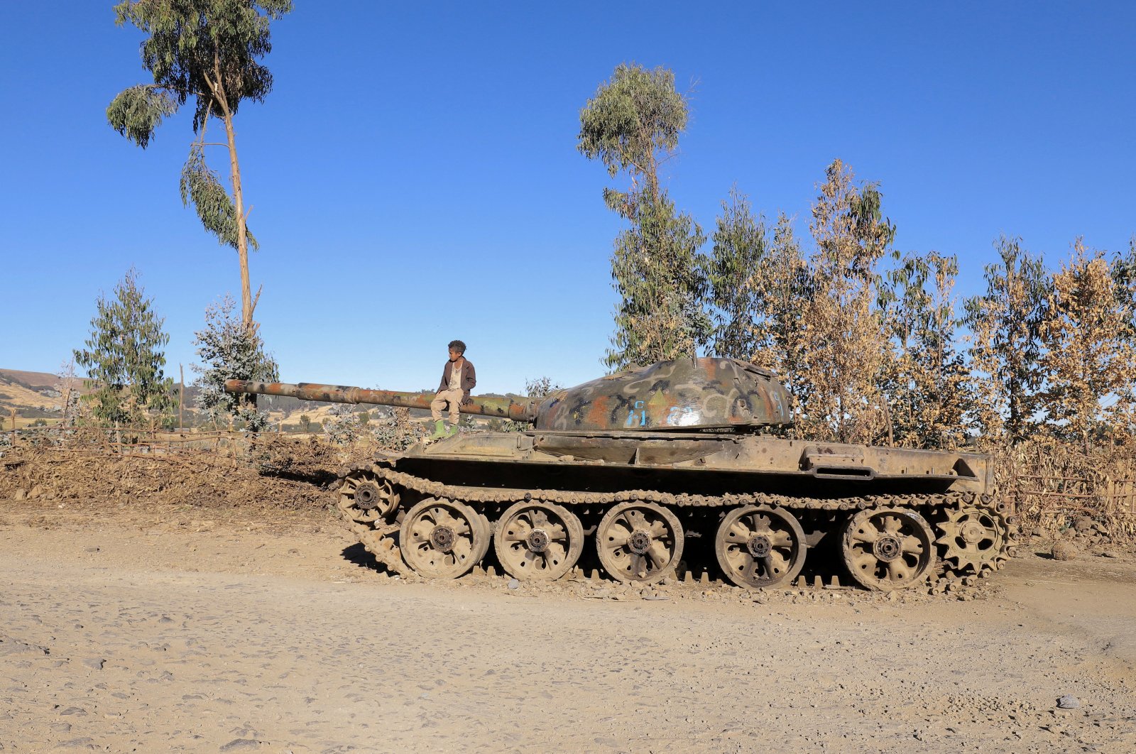 A boy sits on the barrel of a military tank destroyed recently during fighting between the Ethiopian National Defense Force (ENDF) and the Tigray People&#039;s Liberation Front (TPLF) forces in Damot Kebele of Amhara region, Ethiopia, Dec. 7, 2021. (Reuters Photo)