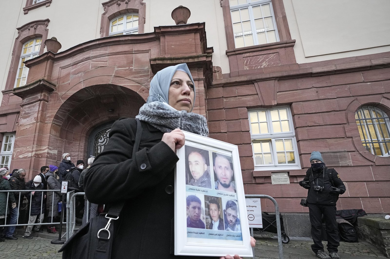 Yasmen Almashan holds pictures of her five brothers who died in Syria before the verdict was announced in front of the court in Koblenz, Germany, Jan. 13, 2022. (AP Photo)