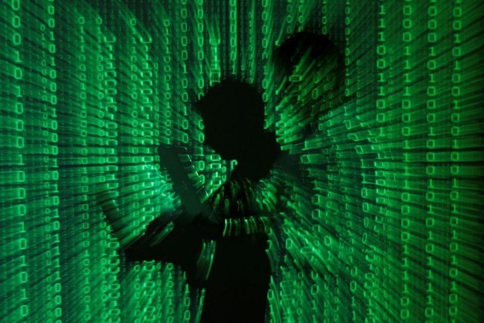 An illustration picture shows a projection of binary code on a man holding a laptop computer, in an office in Warsaw, Poland, June 24, 2013. (Illustration by Kacper Pempel via Reuters)