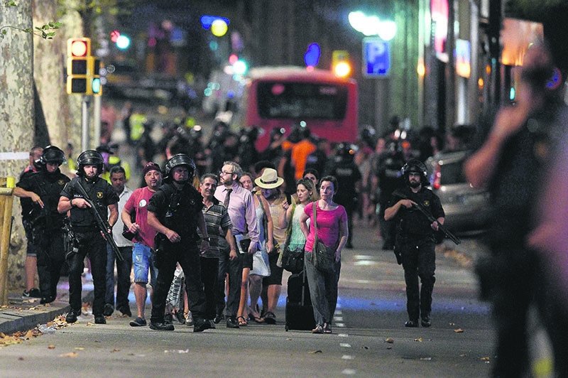 Police accompany people outside a cordoned-off area after a van plowed into a crowd, killing 13 and injuring more than 100 on the Rambla in Barcelona, Spain, Aug. 17, 2017.