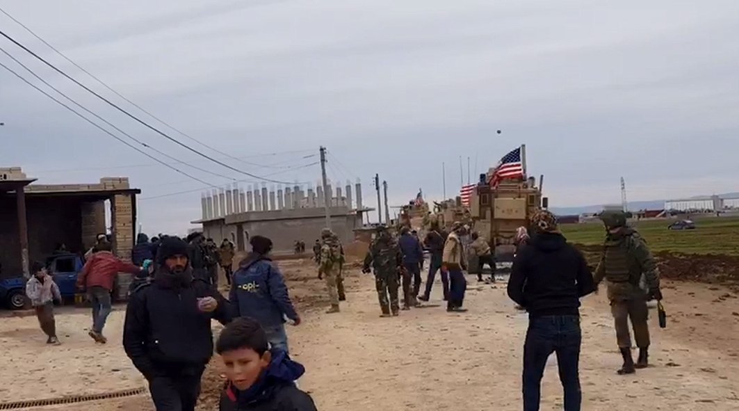 People gather near U.S military vehicles in the village of Khirbet Amo, near Qamishli, Syria, Feb.12, 2020. (SANA/Handout via Reuters)