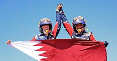 Nasser Al-Attiyah (R) and his co-driver Mathieu Baumel hold a Qatari flag as they celebrate the win, in Jeddah, Saudi Arabia, Jan. 14, 2022. (AFP PHOTO)