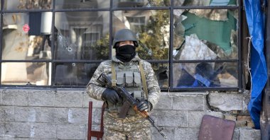 A Kazakhstan soldier guards an area in front of a bullet-pierced window of a street shop in Almaty, Kazakhstan, Jan. 14, 2022. (AP Photo)