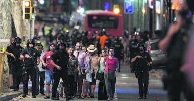 Police accompany people outside a cordoned-off area after a van plowed into a crowd, killing 13 and injuring more than 100 on the Rambla in Barcelona, Spain, Aug. 17, 2017.