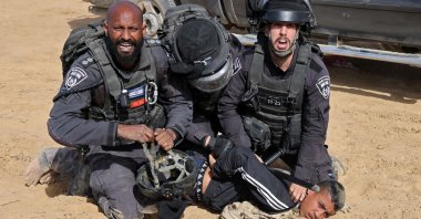 Three heavily armed Israeli officers pose as they brutally detain a child, as Bedouins protest in the southern Israeli village of Sawe al-Atrash in the Negev Desert against an afforestation project, Jan. 12, 2022. (AFP Photo)