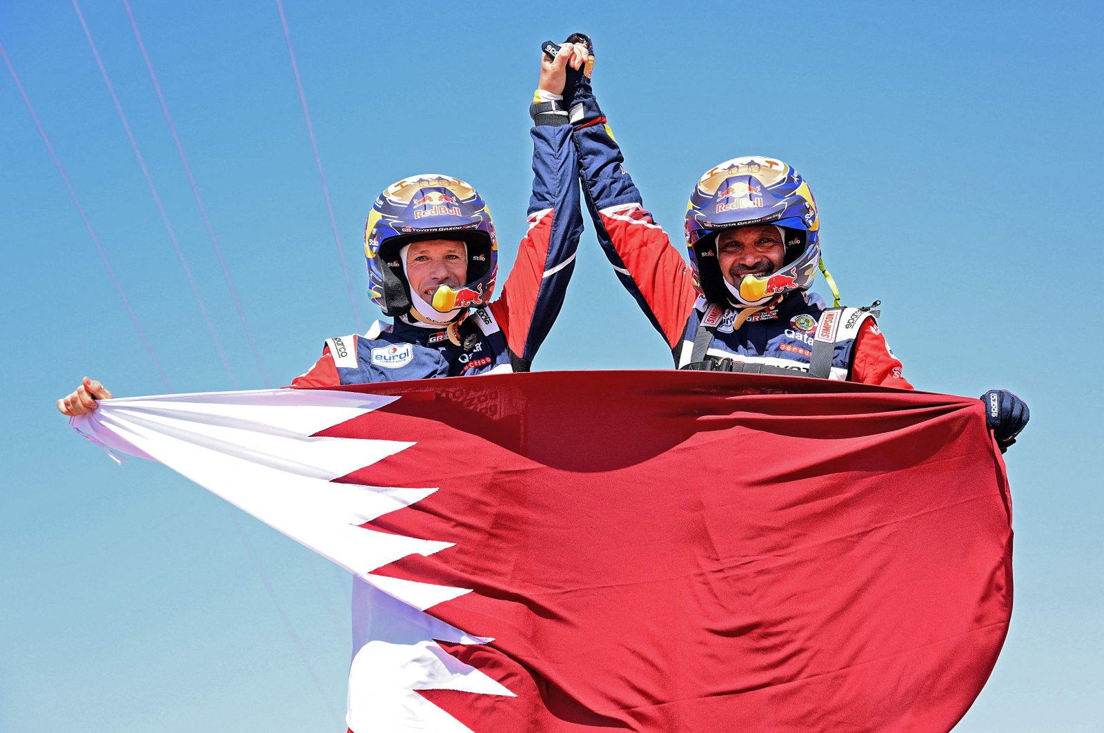Nasser Al-Attiyah (R) and his co-driver Mathieu Baumel hold a Qatari flag as they celebrate the win, in Jeddah, Saudi Arabia, Jan. 14, 2022. (AFP PHOTO)