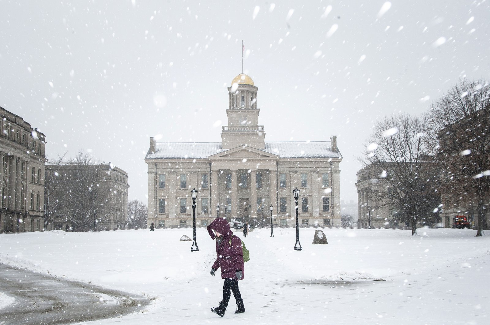 A person walks past the Old Capitol Building as snow falls during a winter storm warning, in Iowa City, Iowa, Jan. 14, 2022. (Joseph Cress/Iowa City Press-Citizen via AP)