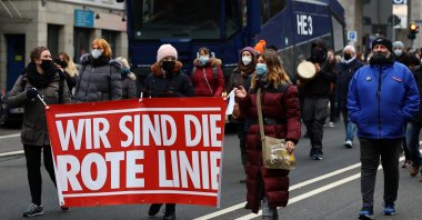 Demonstrators carrying a banner reading &quot;We are the red line&quot; walk past a police water cannon during a protest against government measures to curb the spread of COVID-19 in Frankfurt, Germany, Jan. 15, 2022. (Reuters)