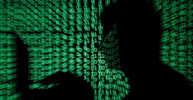A man holds a laptop computer as cyber code is projected on him in this illustration picture taken on May 13, 2017. (Reuters Photo)