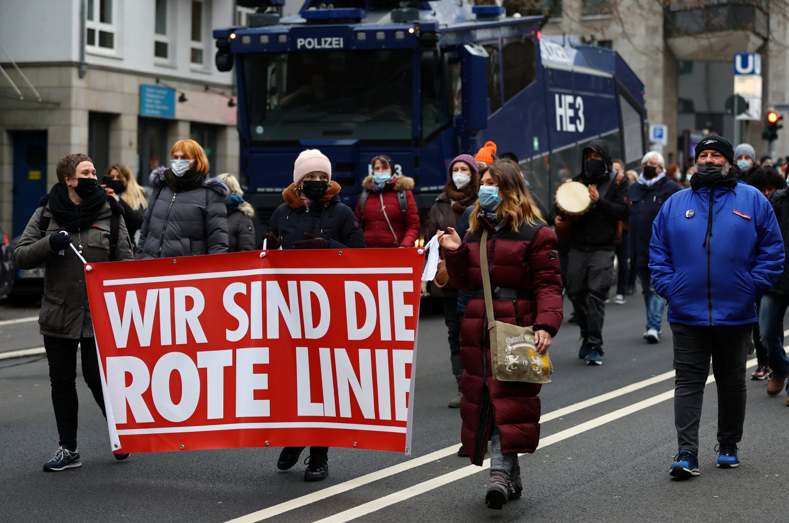 Demonstrators carrying a banner reading &quot;We are the red line&quot; walk past a police water cannon during a protest against government measures to curb the spread of COVID-19 in Frankfurt, Germany, Jan. 15, 2022. (Reuters)