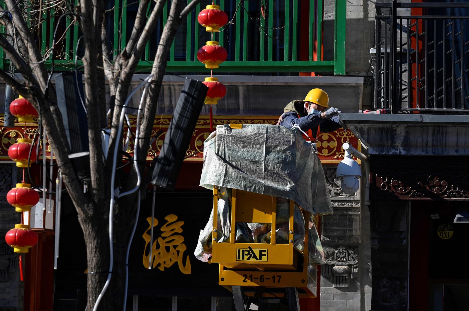 A worker renovates a shopfront along a business street in Beijing, China, Jan. 13, 2022. (AFP Photo)