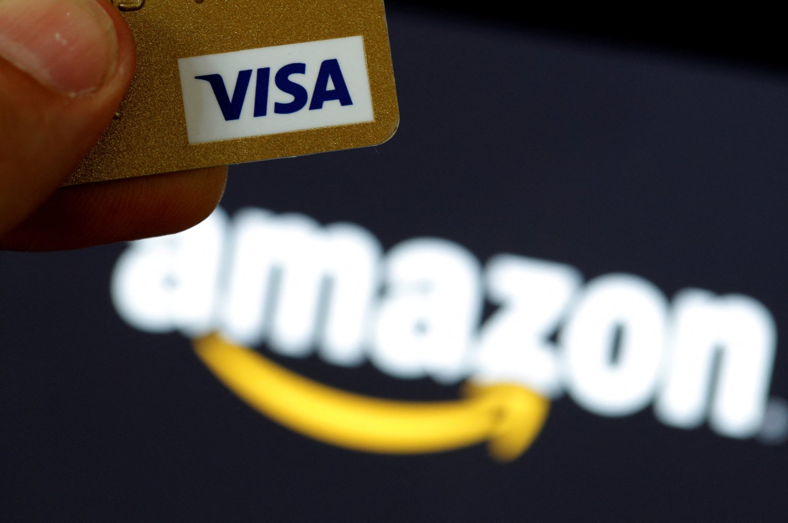 A visa credit card is held in front of an Amazon logo in this picture illustration, Sept. 6, 2017. (Reuters Photo)