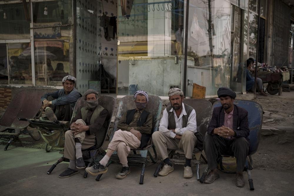 Workers sit on their wheelbarrows as they wait to be hired on the side of the road in Kabul, Afghanistan, Oct. 8, 2021. (AP Photo)