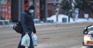 A man wearing a face mask and carrying shopping bags crosses the street in the center of Edmonton, Alberta, Canada, Jan. 14, 2021. (Reuters Photo)
