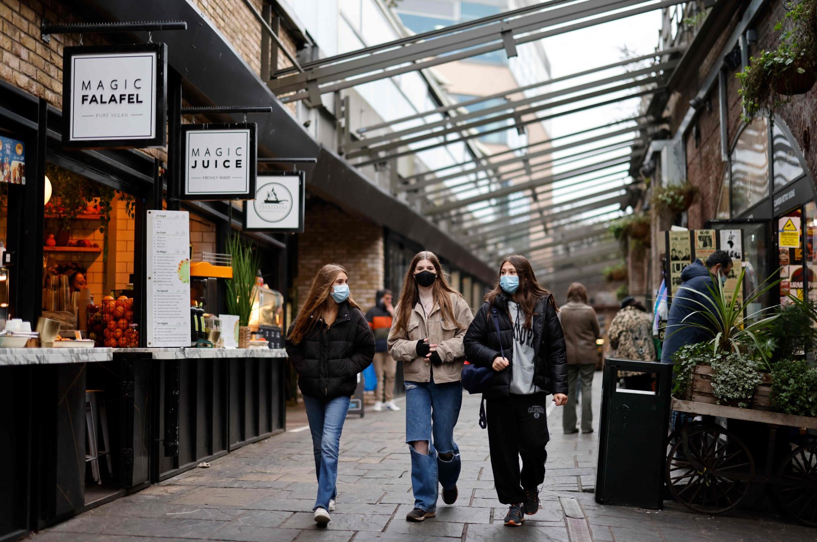 Shoppers wearing face coverings to combat the spread of the coronavirus, walk past stores in Camden Market in London, U.K., Jan. 7, 2022. (AFP Photo)