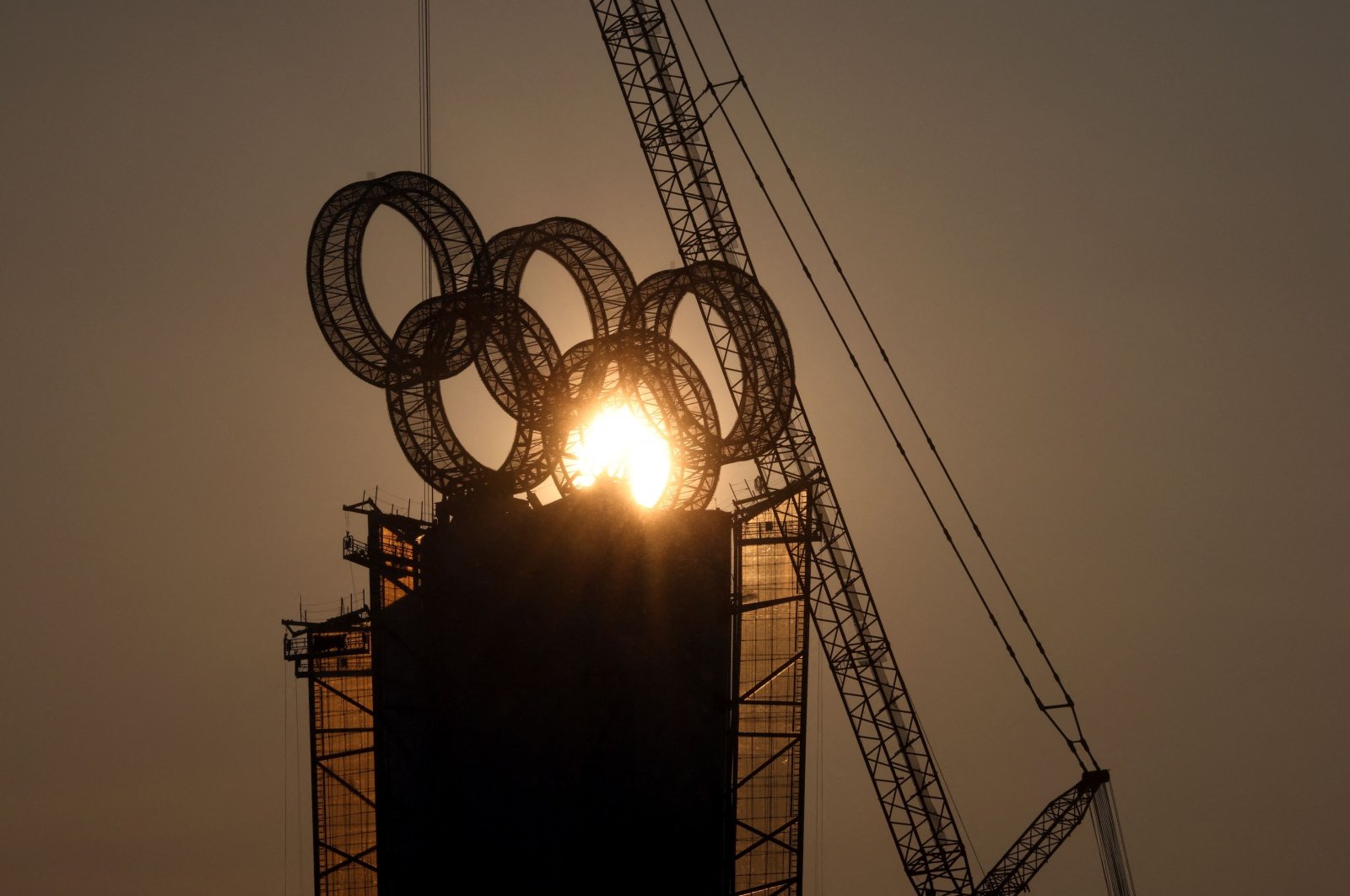 The sun sets behind the Olympic Rings atop a tower near the Yanqing cluster of Beijing 2022 Winter Olympics, in Beijing, China, January 19, 2022. REUTERS/Thomas Peter