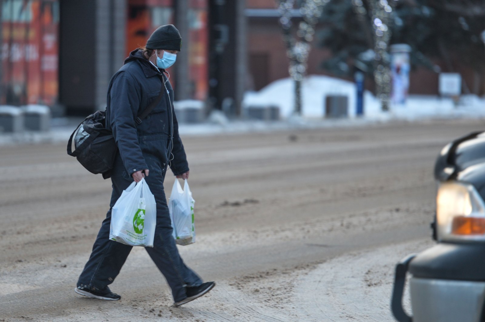 A man wearing a face mask and carrying shopping bags crosses the street in the center of Edmonton, Alberta, Canada, Jan. 14, 2021. (Reuters Photo)