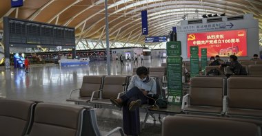Passengers wearing face masks to help protect against the coronavirus rest at Pudong International Airport in Shanghai, China, July 25, 2021. (AP Photo)