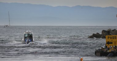 A boat slices through a tsunami surge at the mouth of the Santa Cruz Small Craft Harbor in California, U.S., Jan. 15, 2022. (AP Photo)