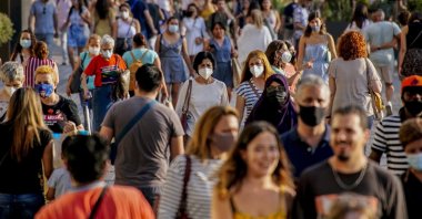 People wearing a face mask to protect against the spread of coronavirus walk along a street in downtown Barcelona, Spain, July 3, 2021. (AP Photo)