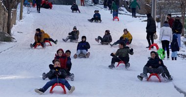 Children ride sleds through a snowy street in Ladik district in Samsun, northern Turkey, Jan. 18, 2022. (AA PHOTO)