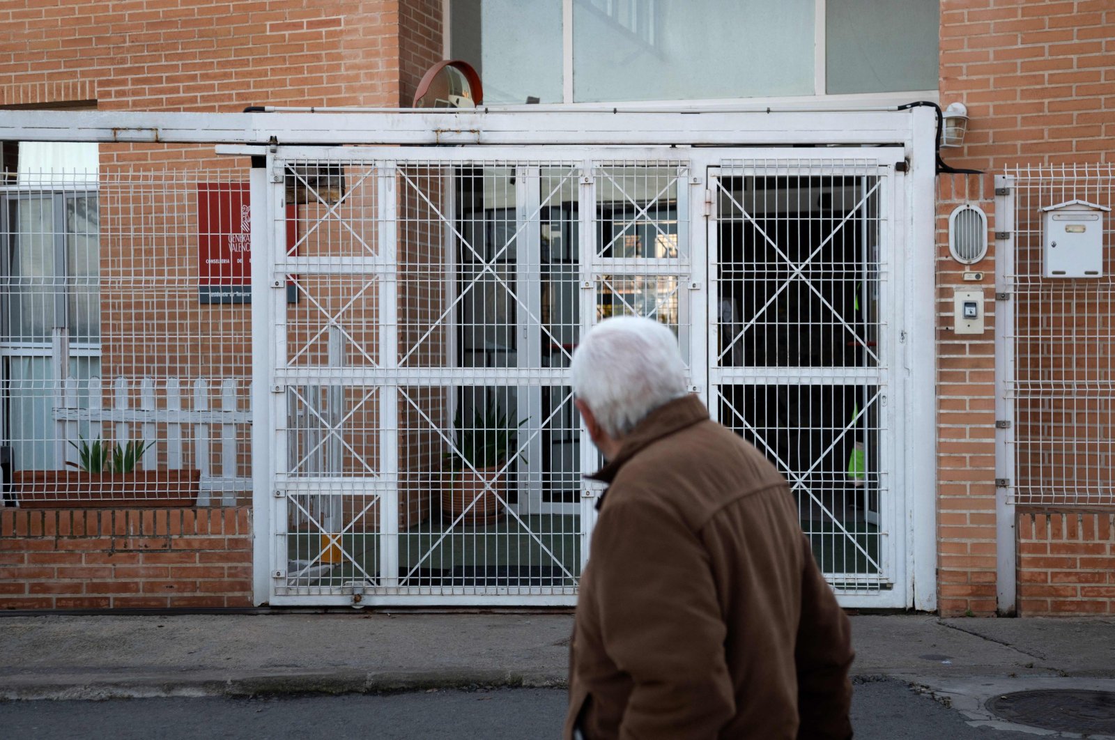 A man walks past the retirement home where a fire broke out overnight in Moncada near Valencia, Spain, on Jan. 19, 2022. (Photo by Jose Jordan / AFP)