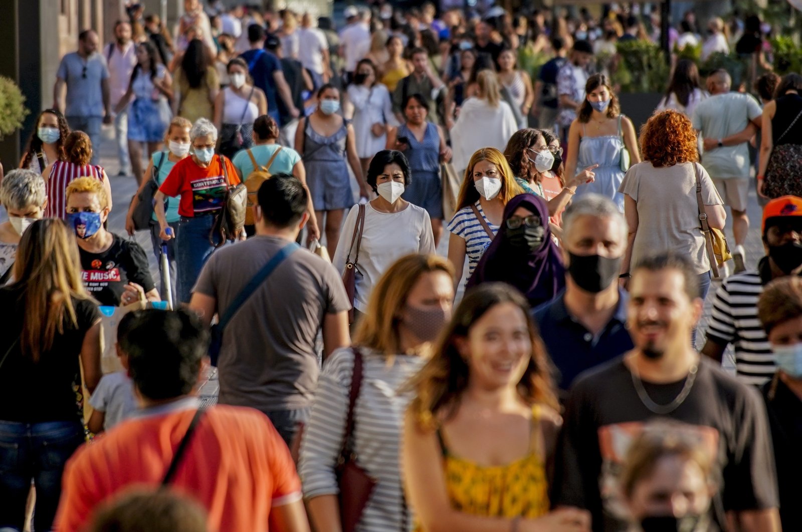 People wearing a face mask to protect against the spread of coronavirus walk along a street in downtown Barcelona, Spain, July 3, 2021. (AP Photo)