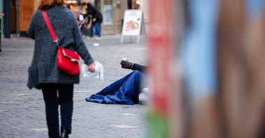 A homeless man begs for money as people walk past him on a pedestrian shopping street in Halle (Saale), eastern Germany, Jan. 19, 2022. (AFP Photo)