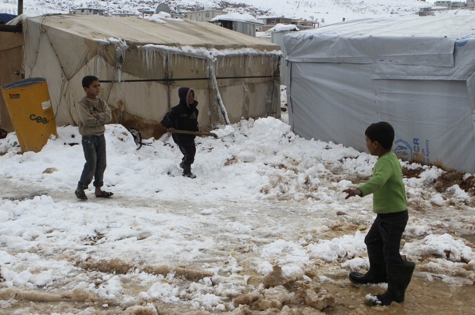A Syrian refugee child shovels snow outside a tent in Aarsal town in eastern Bekaa, Lebanon, Dec. 13, 2013. (Reuters Photo)