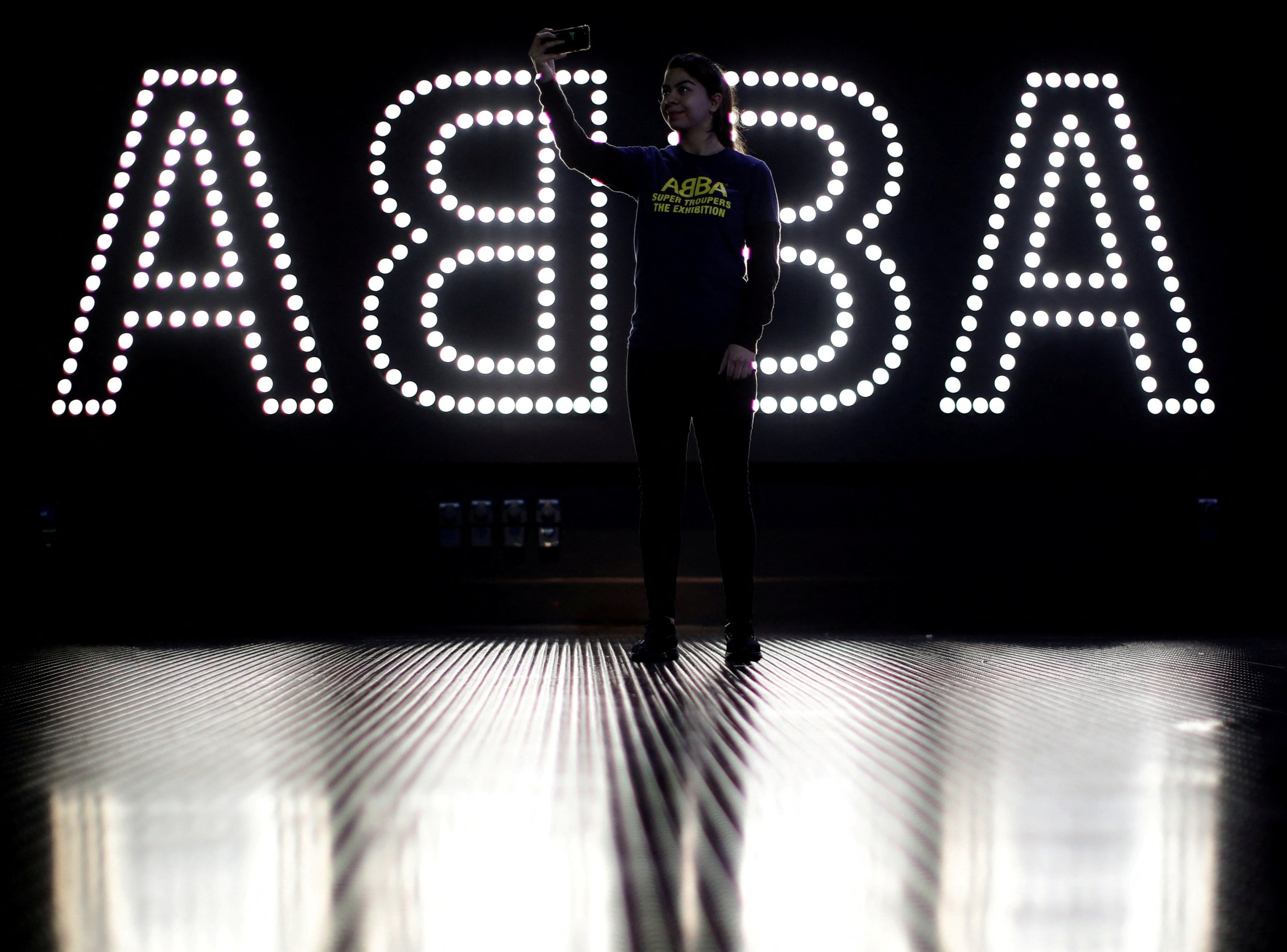 A staff member takes a selfie in front of an ABBA neon sign during the ABBA: Super Troupers The Exhibition at the O2 in London, Britain, Dec. 5, 2019. (Reuters Photo)