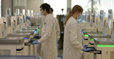 Research assistants watch the sequencing machines analyzing the genetic material of COVID-19 cases at the Wellcome Sanger Institute, Genome Campus, Hinxton, Cambridgeshire, U.K., Jan. 7, 2022. (AP Photo)