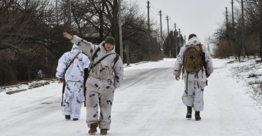 A Ukrainian soldier waves at a photographer as he and his comrades patrol a street toward the frontline with Russia-backed separatists in Verkhnotoretske village in Yasynuvata district, Donetsk region, eastern Ukraine, Jan. 22, 2022. (AP Photo)