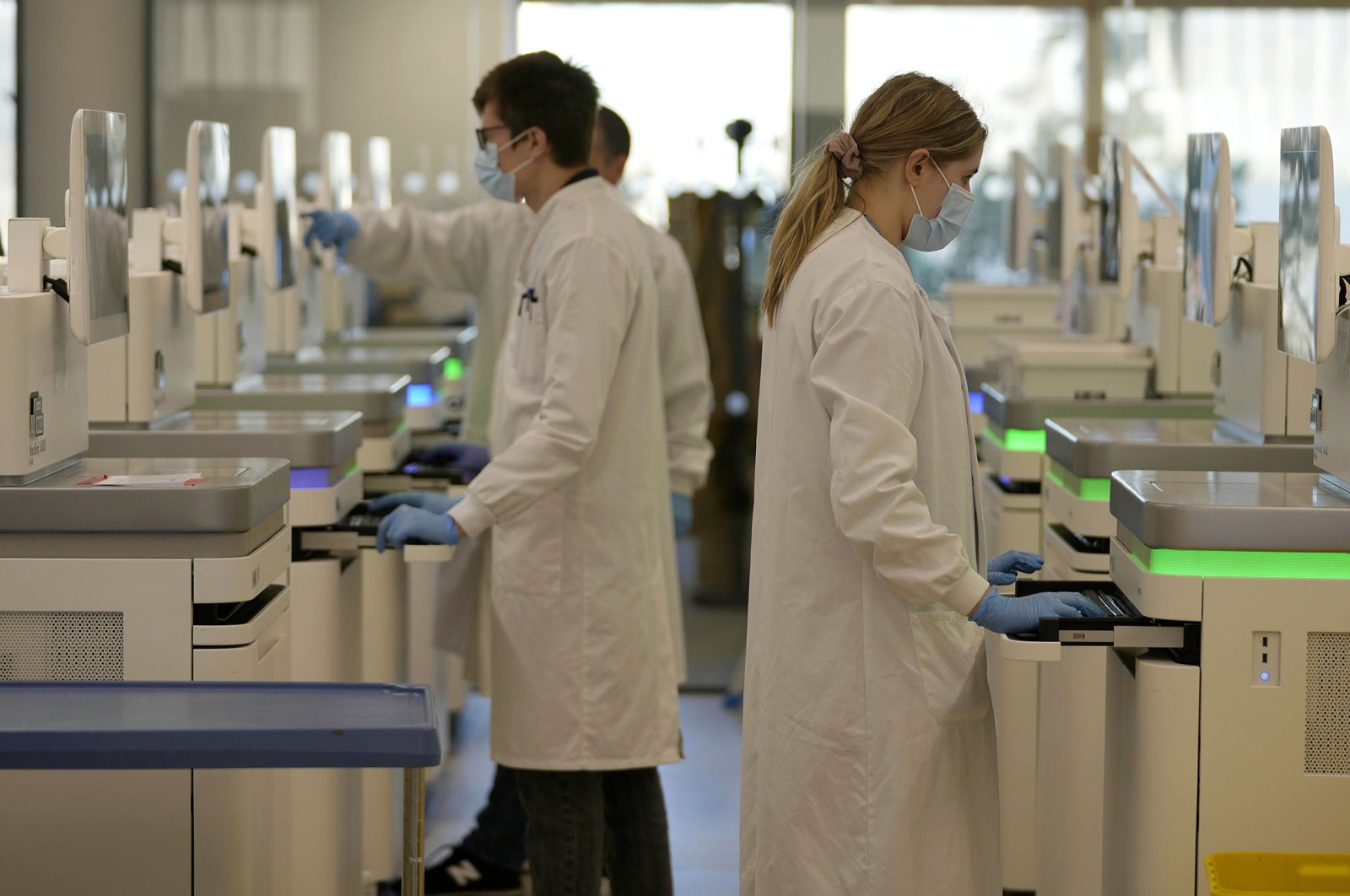 Research assistants watch the sequencing machines analyzing the genetic material of COVID-19 cases at the Wellcome Sanger Institute, Genome Campus, Hinxton, Cambridgeshire, U.K., Jan. 7, 2022. (AP Photo)