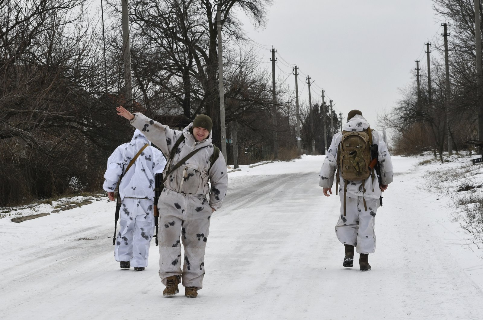 A Ukrainian soldier waves at a photographer as he and his comrades patrol a street toward the frontline with Russia-backed separatists in Verkhnotoretske village in Yasynuvata district, Donetsk region, eastern Ukraine, Jan. 22, 2022. (AP Photo)