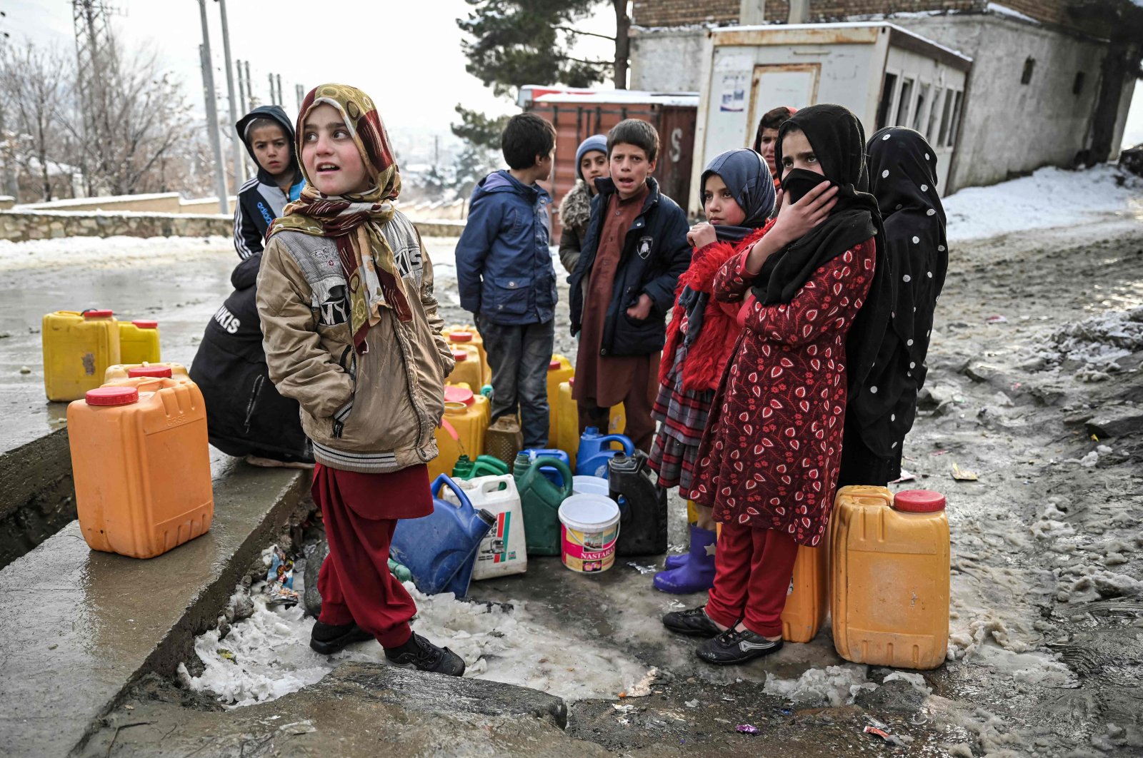 Children wait to fill jerry cans with waters on a cold day in Kabul, Afghanistan, Jan. 22, 2022. (AFP Photo)