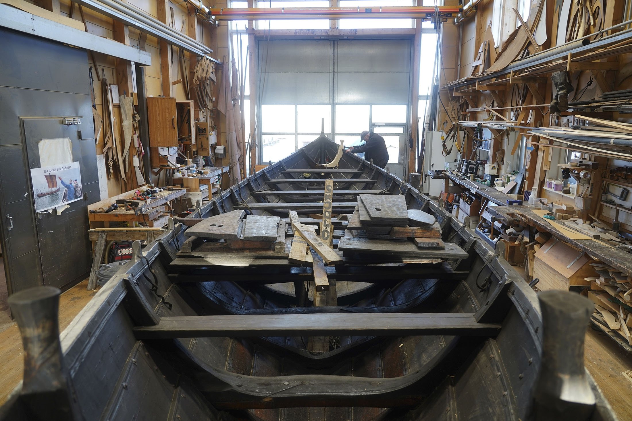 Seorang pria memperbaiki perahu kayu sepanjang 10 meter, dibangun dengan tradisi perahu klinker Nordik, di galangan kapal Museum Kapal Viking di Roskilde, Denmark, 17 Januari 2022. (AP Photo)