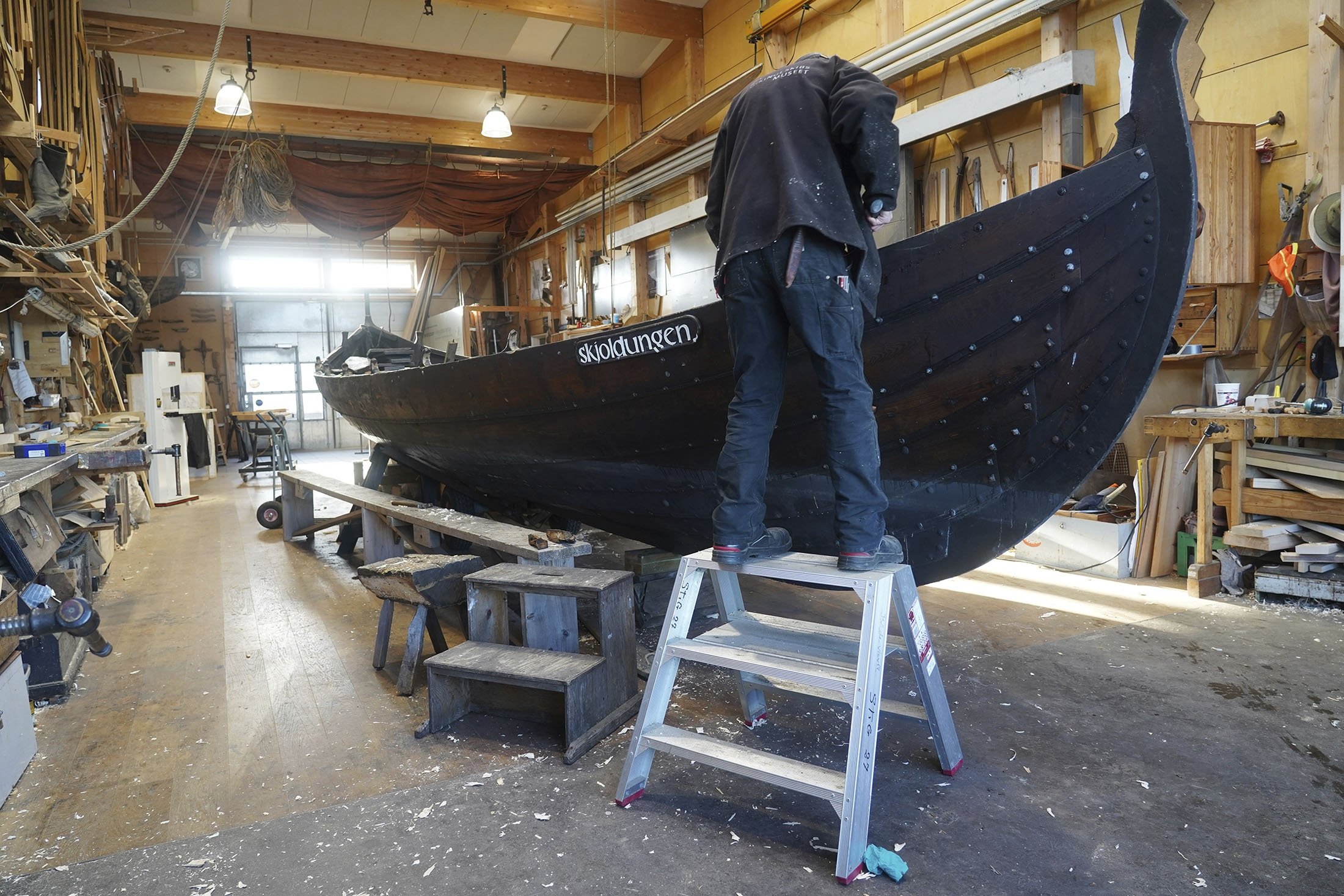 Seorang pria memperbaiki perahu kayu sepanjang 10 meter, dibangun dengan tradisi perahu klinker Nordik, di galangan kapal Museum Kapal Viking di Roskilde, Denmark, 17 Januari 2022. (AP Photo)