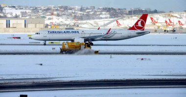 A Turkish Airlines aircraft is seen as snow plough cleans runway at Istanbul Airport, Jan. 24, 2022. (DHA Photo)