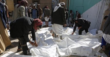 People look at the covered bodies of casualties from a Saudi-led coalition airstrike that killed at least 87 people, in a stronghold of Houthi rebels on the border with Saudi Arabia, in the northern Saada province of Yemen, Jan. 22, 2022. (AP Photo)