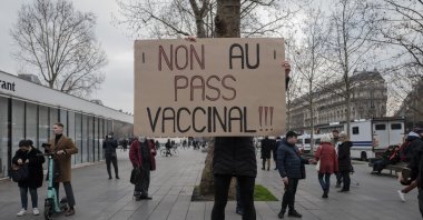 A demonstrator holds a placard that reads &quot;No to vaccine pass&quot; in opposition to COVID-19 vaccine passes and vaccinations, during a rally in Paris, France, Jan. 22, 2022. (AP Photo)