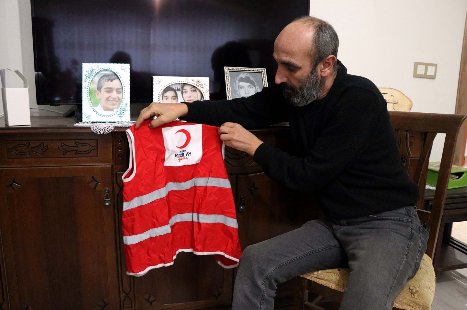 Meriç Dişli looks at a vest worn by his late son Miraç and photos of his son and wife, in Elazığ, eastern Turkey, Jan. 23, 2022. (AA Photo)
