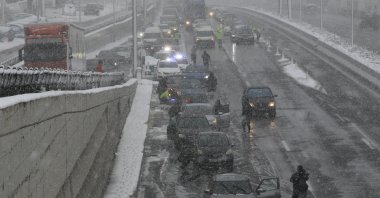 Drivers put chains on their cars on National Road amid snowfall in Athens, Greece, Jan. 24, 2022. (EPA-EFE Photo)